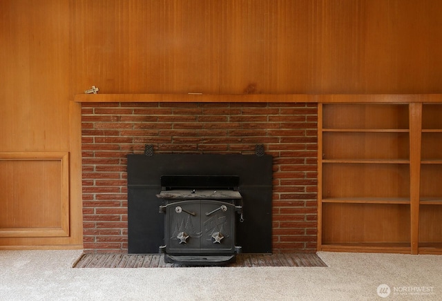 interior details with a fireplace with flush hearth, wooden walls, and carpet flooring
