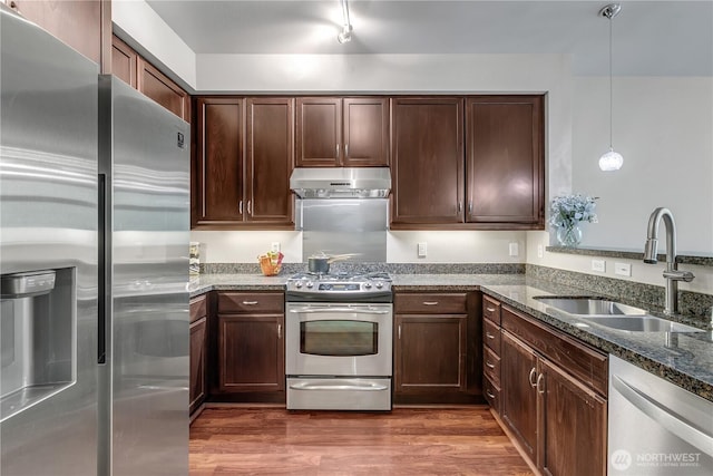 15700 116th Ave NE Unit 205, Bothell, WA 98011 - kitchen with under cabinet range hood, dark stone countertops, a sink, dark wood-type flooring, and appliances with stainless steel finishes