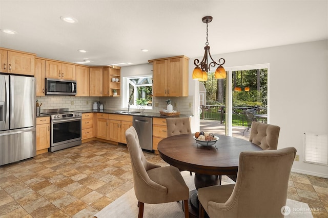 kitchen featuring plenty of natural light, dark countertops, open shelves, stone tile flooring, and stainless steel appliances