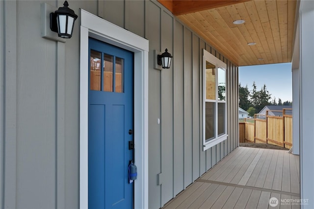 entrance to property with board and batten siding, a porch, and fence