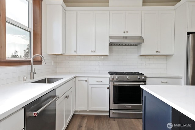 kitchen featuring under cabinet range hood, light countertops, a sink, appliances with stainless steel finishes, and white cabinetry