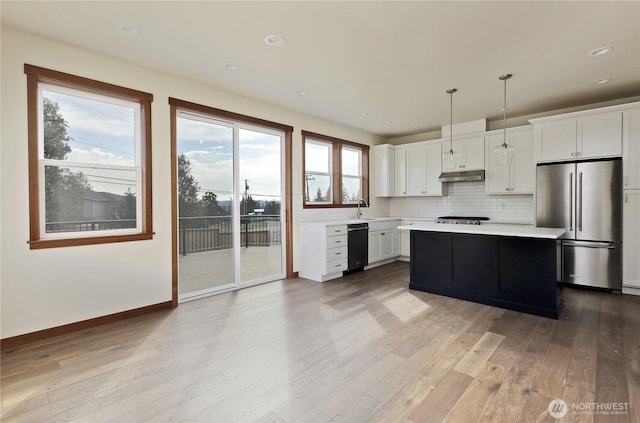 kitchen with under cabinet range hood, light countertops, wood finished floors, appliances with stainless steel finishes, and white cabinetry