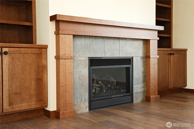 details with baseboards, a tiled fireplace, and wood finished floors