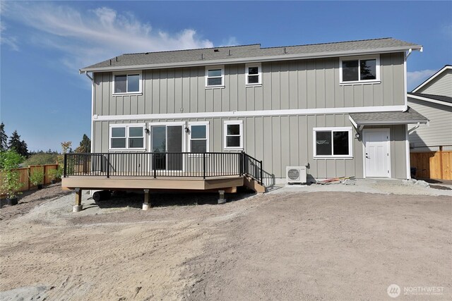 rear view of house featuring roof with shingles, fence, and a deck