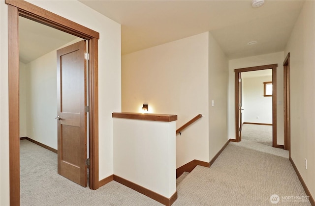corridor with baseboards, carpet, and an upstairs landing