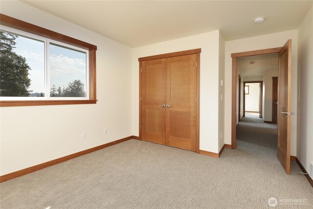 unfurnished bedroom with light colored carpet, baseboards, and a closet