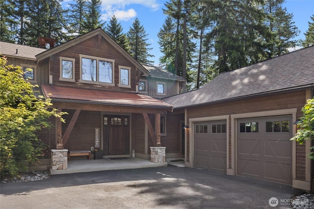 craftsman house with an attached garage, a porch, and aphalt driveway