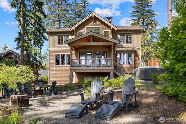 back of property featuring board and batten siding, stairway, a chimney, and an outdoor fire pit