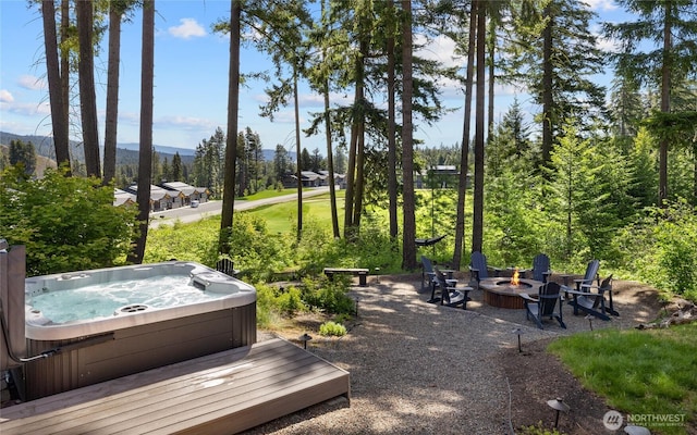 exterior space featuring view of golf course, a hot tub, a fire pit, and a mountain view