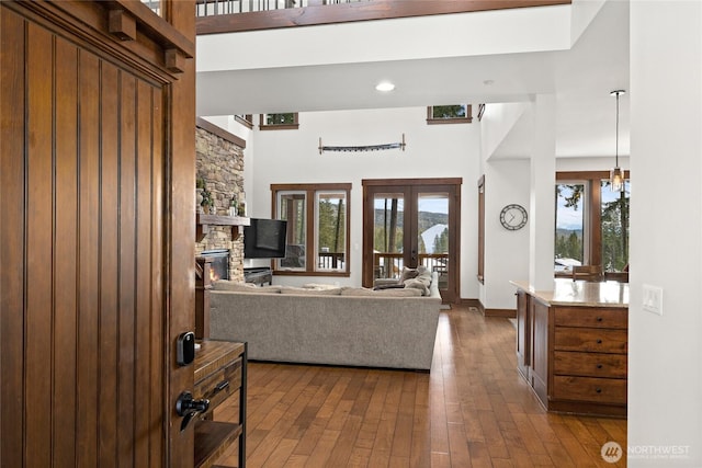 living room featuring french doors, dark wood finished floors, a high ceiling, and a fireplace