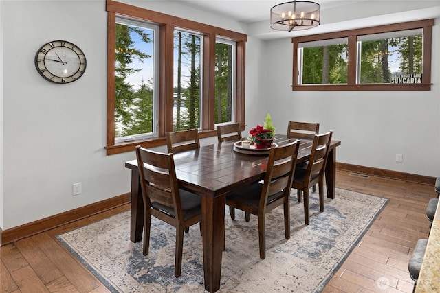 dining area featuring wood-type flooring, baseboards, a notable chandelier, and visible vents