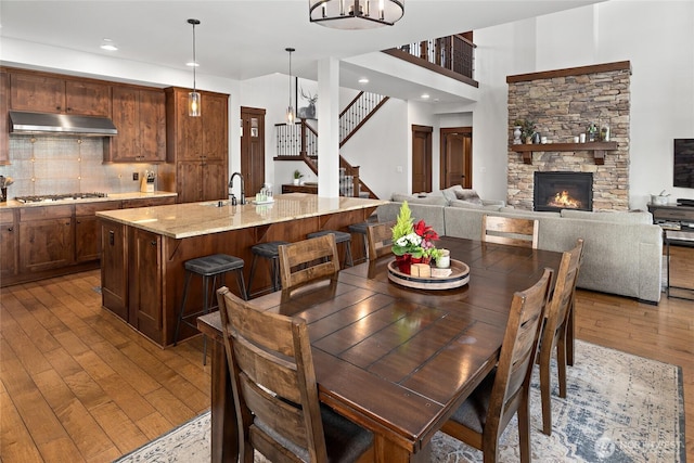 dining room with stairway, a stone fireplace, recessed lighting, and hardwood / wood-style floors