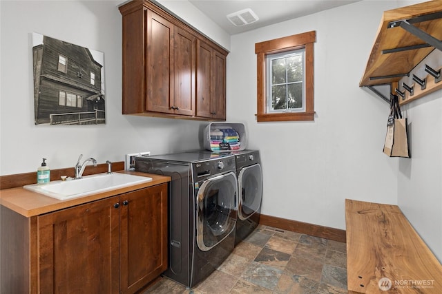 laundry room with cabinet space, a sink, baseboards, visible vents, and washing machine and dryer