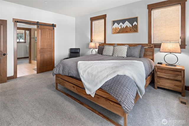 bedroom featuring a barn door and light carpet