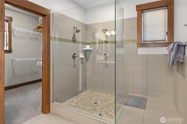 full bathroom featuring tile patterned flooring, walk in shower, and a spacious closet