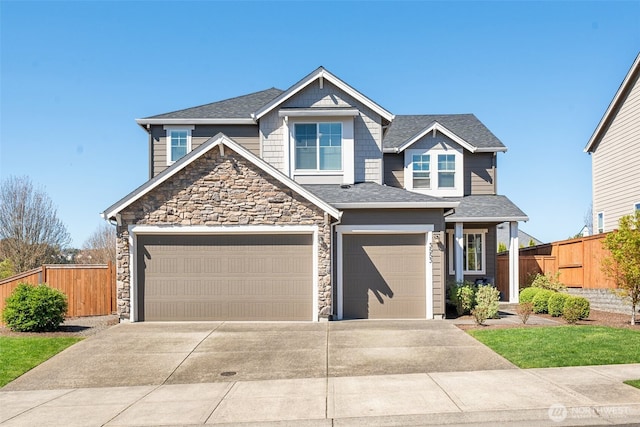 craftsman house with fence, a shingled roof, an attached garage, driveway, and stone siding