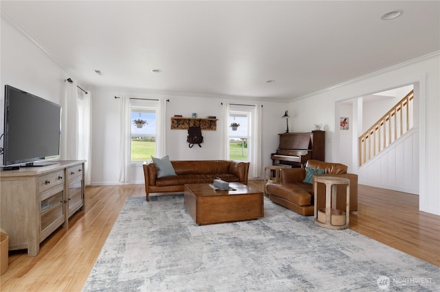 living room featuring crown molding, light wood-style flooring, visible vents, and stairway