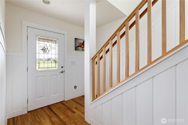 entryway featuring a decorative wall, wood finished floors, and a wainscoted wall