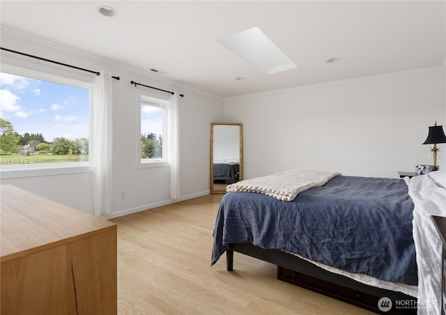 bedroom with visible vents, ornamental molding, baseboards, light wood-style flooring, and a skylight