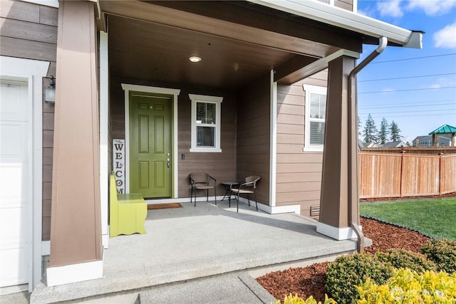 entrance to property featuring a porch and fence
