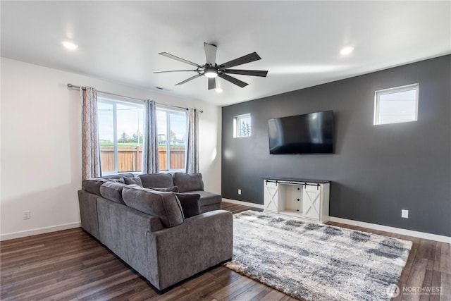 living room featuring baseboards, dark wood-style floors, ceiling fan, and a healthy amount of sunlight