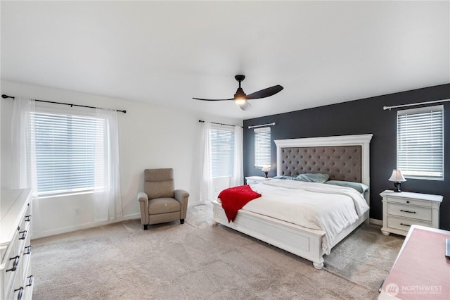 bedroom featuring a ceiling fan, light carpet, and multiple windows