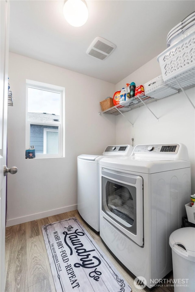 laundry room featuring laundry area, visible vents, baseboards, washer and clothes dryer, and light wood finished floors