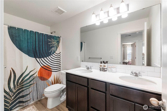 bathroom featuring visible vents, a sink, wood finished floors, and toilet