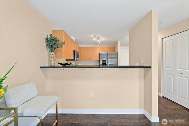 107 20th Ave Unit 306, Seattle, WA 98122 - kitchen featuring appliances with stainless steel finishes, a peninsula, dark wood-type flooring, and baseboards