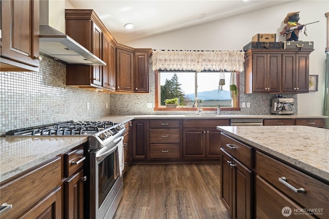 kitchen with a sink, dark wood finished floors, wall chimney exhaust hood, lofted ceiling, and gas stove