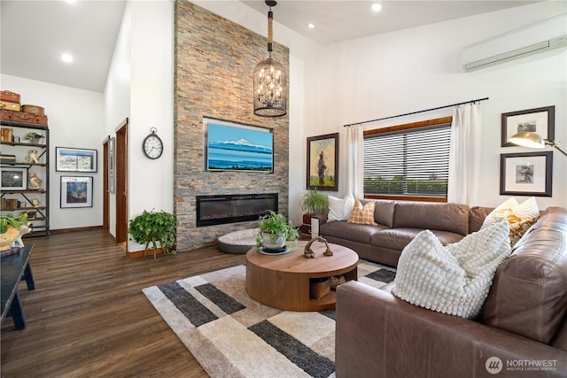 living area with a stone fireplace, a towering ceiling, dark wood-type flooring, and a wall unit AC