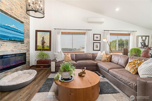 living area featuring wood finished floors, a fireplace, a wall unit AC, a chandelier, and high vaulted ceiling