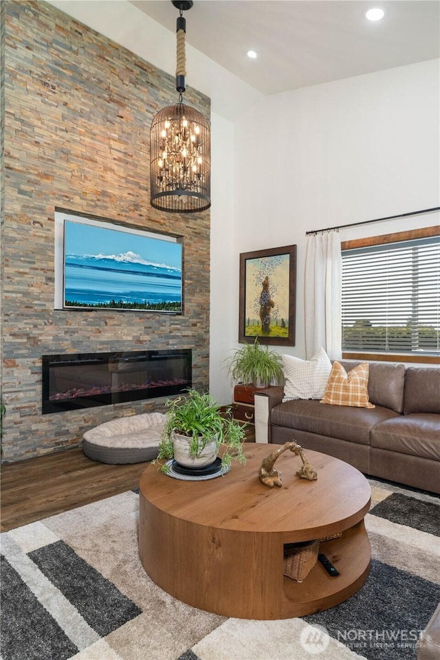 living room featuring recessed lighting, a notable chandelier, high vaulted ceiling, wood finished floors, and a fireplace