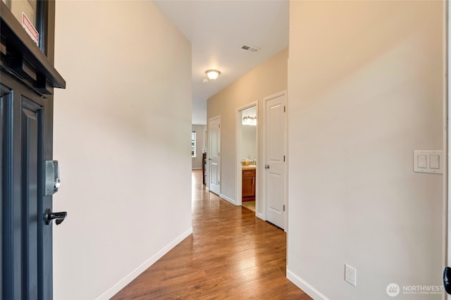 hallway featuring wood finished floors and baseboards