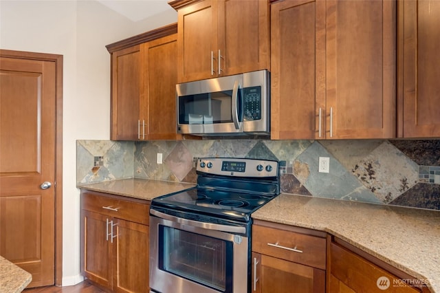 kitchen with appliances with stainless steel finishes, brown cabinetry, decorative backsplash, and light stone counters