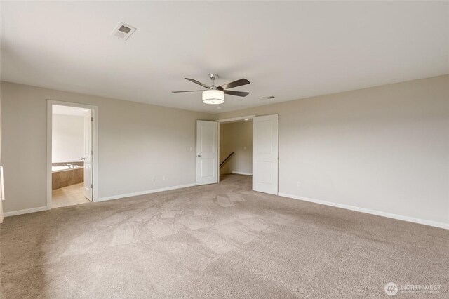 unfurnished bedroom featuring light carpet, baseboards, ceiling fan, and ensuite bath