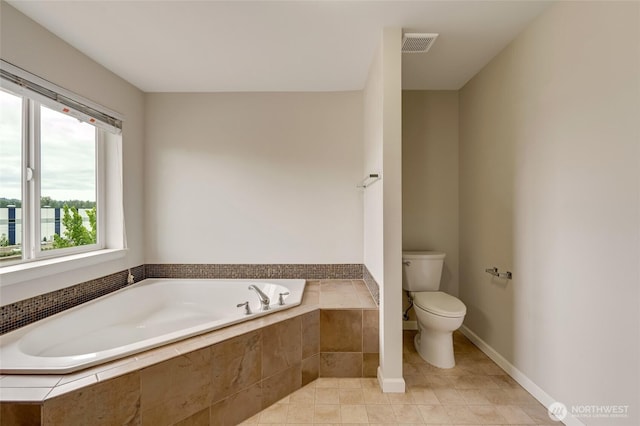 full bath featuring toilet, a garden tub, and tile patterned floors