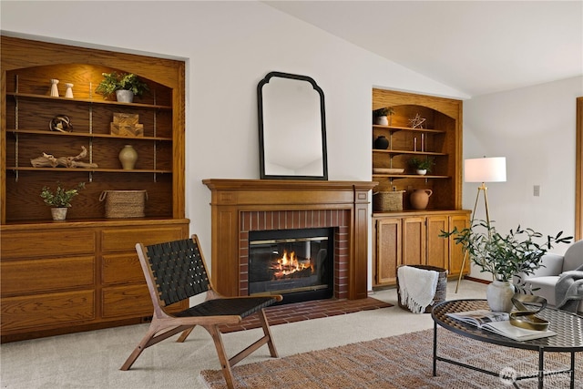 living area with vaulted ceiling, a brick fireplace, and light colored carpet