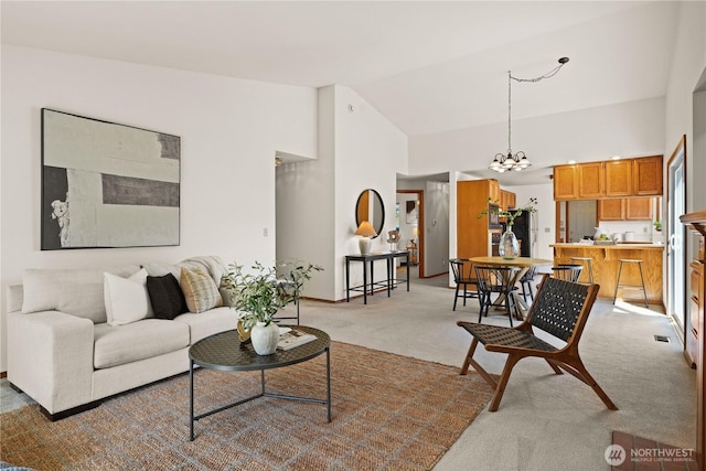 living room with high vaulted ceiling, light carpet, and a chandelier