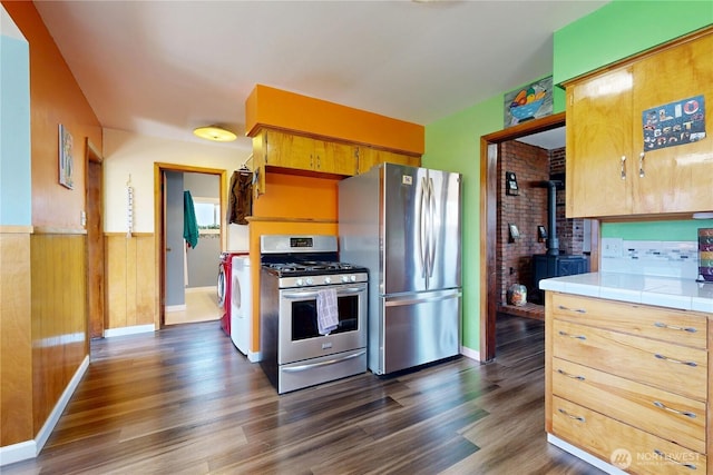 138 SE 5th Ave, Milton-Freewater, OR 97862 - kitchen featuring appliances with stainless steel finishes, tile countertops, a wood stove, dark wood-style floors, and baseboards