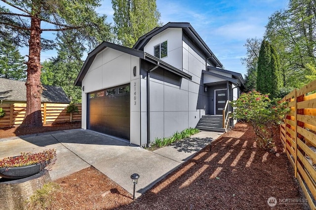 view of side of property with stucco siding, concrete driveway, and fence