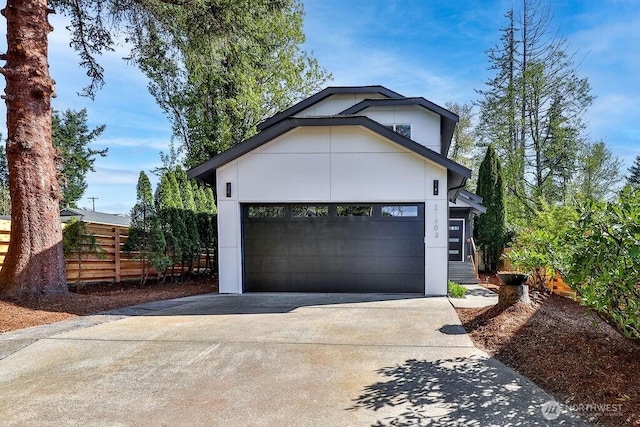 view of front of home with a garage, concrete driveway, and fence