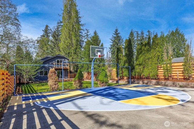 view of basketball court with basketball hoop and fence