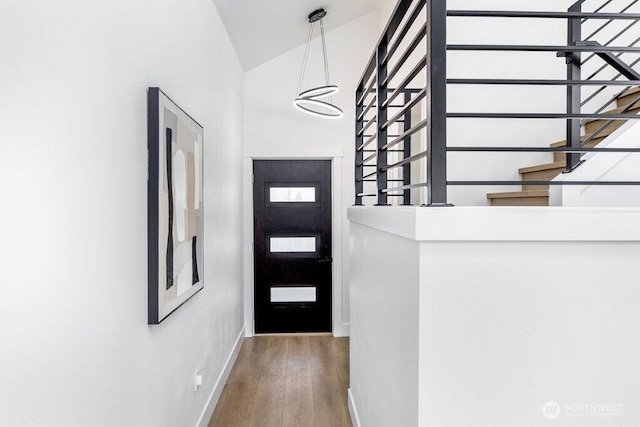 doorway to outside featuring baseboards, wood finished floors, high vaulted ceiling, and stairs