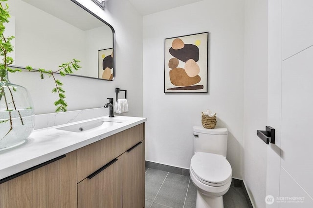 bathroom featuring baseboards, vanity, tile patterned flooring, and toilet