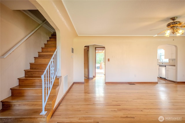 interior space featuring arched walkways, ceiling fan, wood finished floors, and visible vents