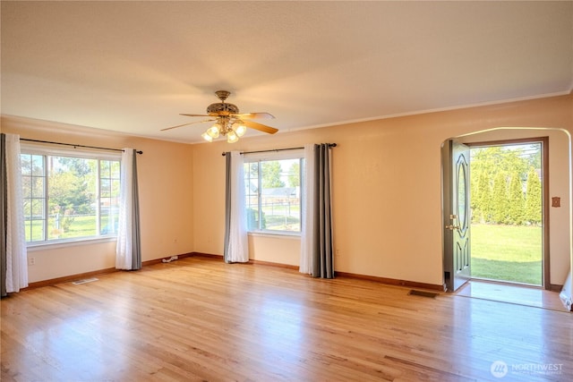 spare room with baseboards, ceiling fan, light wood-type flooring, and visible vents