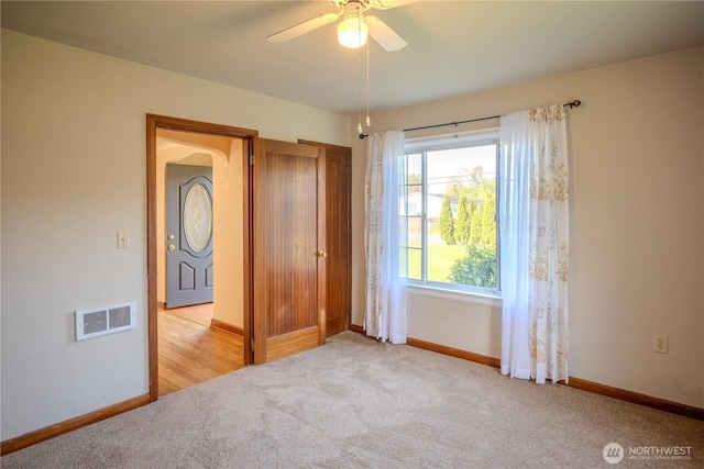 unfurnished bedroom with visible vents, a ceiling fan, baseboards, arched walkways, and carpet flooring