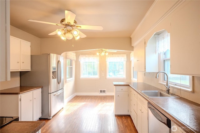 kitchen with white dishwasher, a sink, ceiling fan, and a healthy amount of sunlight