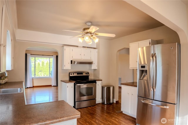 kitchen featuring under cabinet range hood, stainless steel appliances, arched walkways, and dark wood-type flooring